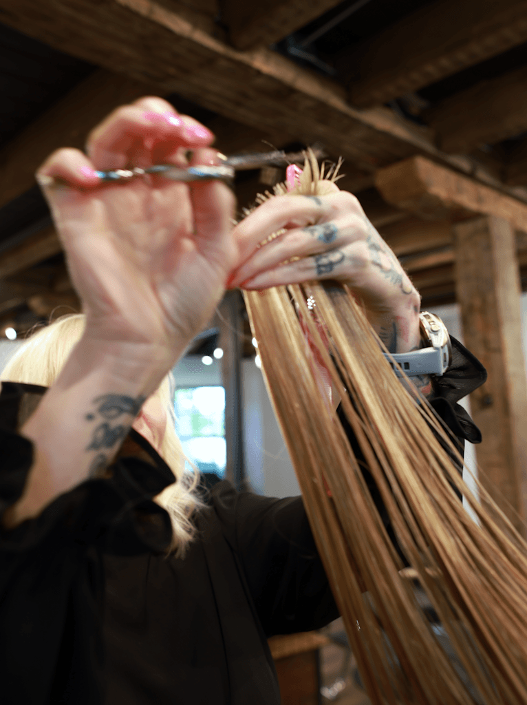 Tatum Spano cutting hair with tattooed hands